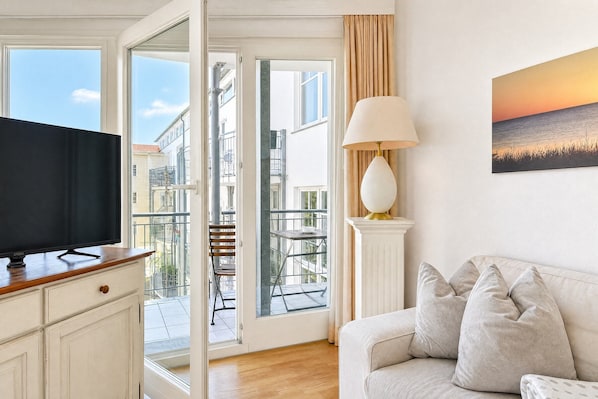 Una sala de estar con televisión, sofá, lámpara y un cuadro.