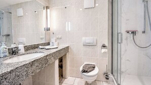 Un baño moderno con encimera de granito, cabina de ducha de vidrio y un inodoro con toalla.