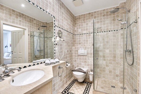 A modern bathroom with a glass-enclosed shower, a large mirror, a sink with a vanity, and a toilet.