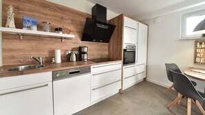 A modern kitchen with a wooden backsplash, stainless steel appliances, and a dining area with a table and chairs.