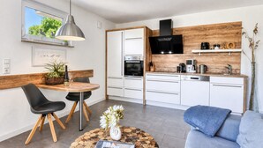 A modern kitchen with white cabinets, a black range hood, and a wooden accent wall.
