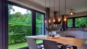 A modern kitchen with large windows, a wooden dining table, and black chairs. - Welcome to Backsteinquartier D in Putbus on Rügen (Putbus)