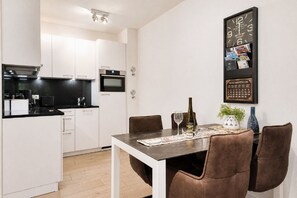 Eine moderne Küche mit weißen Schränken, einer schwarzen Arbeitsplatte und einem eingebauten Backofen.