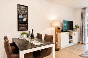 A dining area with a table, chairs, a wine bottle, and a calendar on the wall.