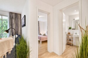 A modern interior with a bed, bedside table, and a bathroom with a mirror and shelves.
