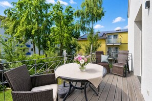 Eine Terrasse mit Korbmöbeln, einem runden Tisch und einem Blumenstrauß.