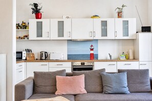 Una cocina moderna con armarios blancos, microondas, tostadora y hervidor.