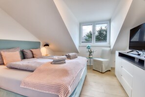 Een moderne slaapkamer met een bed, nachtkastje, lamp en een televisie.