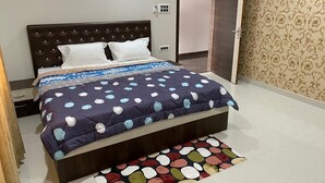 Un dormitorio con cama, mesita de noche, cómoda y puerta.