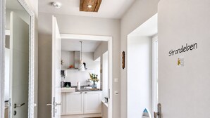 A modern kitchen with white cabinets, a wooden floor, and a hanging pendant light.