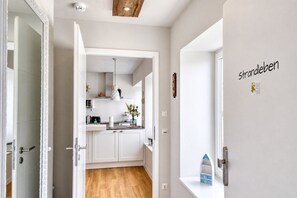 A modern kitchen with white cabinets, a wooden floor, and a hanging pendant light.