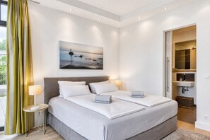 Un dormitorio moderno con una cama grande, lámparas de noche, un cuadro en la pared y vistas al exterior.