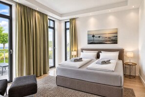 A modern bedroom with a large bed, two bedside lamps, a painting, and a view through the window.