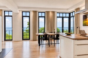 Eine moderne Küche mit großen Fenstern, einem Essbereich und Meerblick.