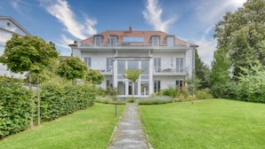 A two-story building with a central entrance, surrounded by well-maintained lawns and hedges.