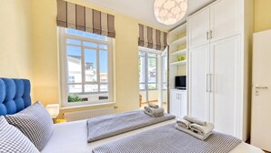 Un dormitorio con cama, dos mesitas de noche, televisión y armario.