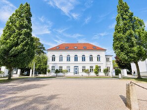 Ein weißes Gebäude mit rotem Ziegeldach, umgeben von Bäumen und einer Schotterzufahrt.