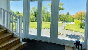 Ein Zimmer mit einer Treppe, die zu einem Balkon mit großen Fenstern führt; es ist mit einem schwarzen Teppich und einem kleinen schwarzen Tisch mit einer Kerze ausgestattet.