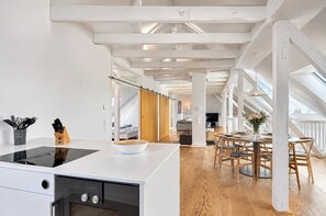 Una cocina moderna con una isla central, armarios de madera y una zona de comedor con una mesa redonda y sillas.