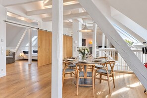 Un loft espacioso con techos altos, vigas a la vista y un comedor con una mesa redonda para seis personas.