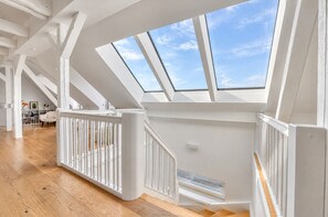 Un loft espacioso con techo alto, tragaluces y piso de madera.