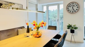 Ein stilvoller Essbereich mit einem Holztisch, Stühlen, einer Blumenvase und einer Uhr an der Wand.