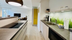 Eine moderne Küche mit einer zentralen Kochinsel, einem eingebauten Backofen und einer Kaffeemaschine.