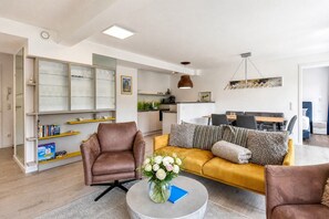 A modern living room with a sofa, armchairs, a coffee table, and a bookshelf.