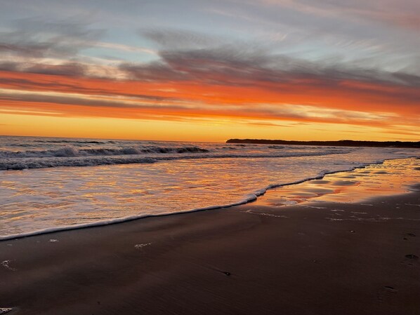 A beach with waves and a sunset.