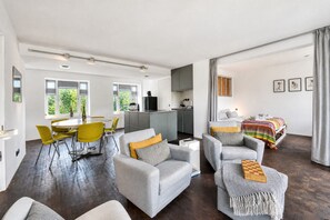A modern living space with a dining area, kitchen, and a bedroom.