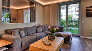 A modern living room with a grey sofa, a wooden coffee table, and a vase with flowers. - Baltic Sea vacation in Meeresrauschen 2 / Villa Vogue Binz: Sea view and front row (Binz)