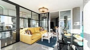 Ein modernes Wohnzimmer mit einem gelben Sofa, einem weißen Couchtisch und einem Glastisch mit Speisen.