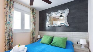 A bedroom with a bed, two pillows, a nightstand, a mirror, and curtains. - Apartamento Zoraida del mar (Mesa del Mar)