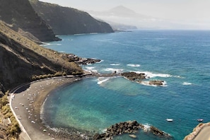 Eine Küstenlandschaft mit einem gewundenen Strand, Felsenformationen und freiem Blick auf den Ozean.