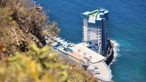 A coastal hotel with a prominent tower, a flat-roofed building, and a view of the sea. - Apartamento Zoraida del mar (Mesa del Mar)