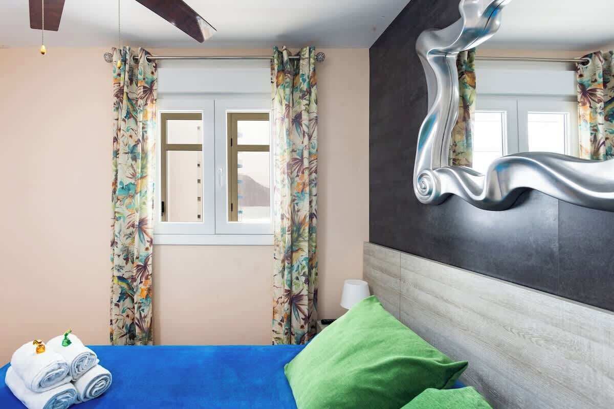 Een hotelkamer met een bed, gordijnen, een spiegel en een raam.
