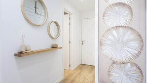 A hallway with a wooden shelf, two round mirrors, and a door. - Beachfront Luxury Apt w/ Sea Views & Pool Access (Puerto de la Cruz)