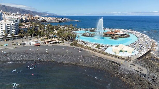 A coastal resort with a central fountain, a beach area, and a pool. - Beachfront Luxury Apt w/ Sea Views & Pool Access (Puerto de la Cruz)