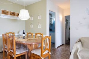 Ein Essbereich mit Holztisch und Stühlen, einer Pendelleuchte und einer Küche im Hintergrund.