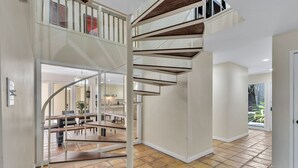 Ein großzügiger Innenraum mit einer modernen Wendeltreppe, einer Küchenzeile und Blick ins Freie.