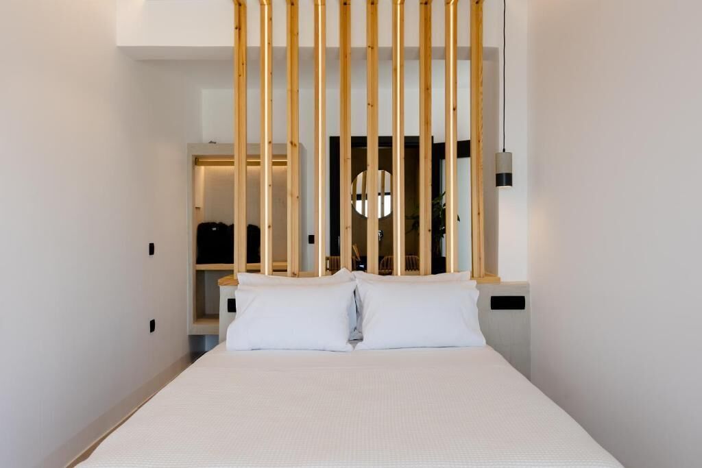 A modern hotel room with a bed, a wooden partition, and a circular light fixture.
