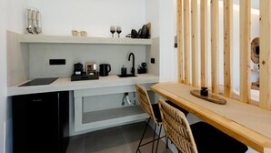 Een moderne keuken met witte kasten, een zwarte vaatwasser, een houten eettafel en een rieten stoel.