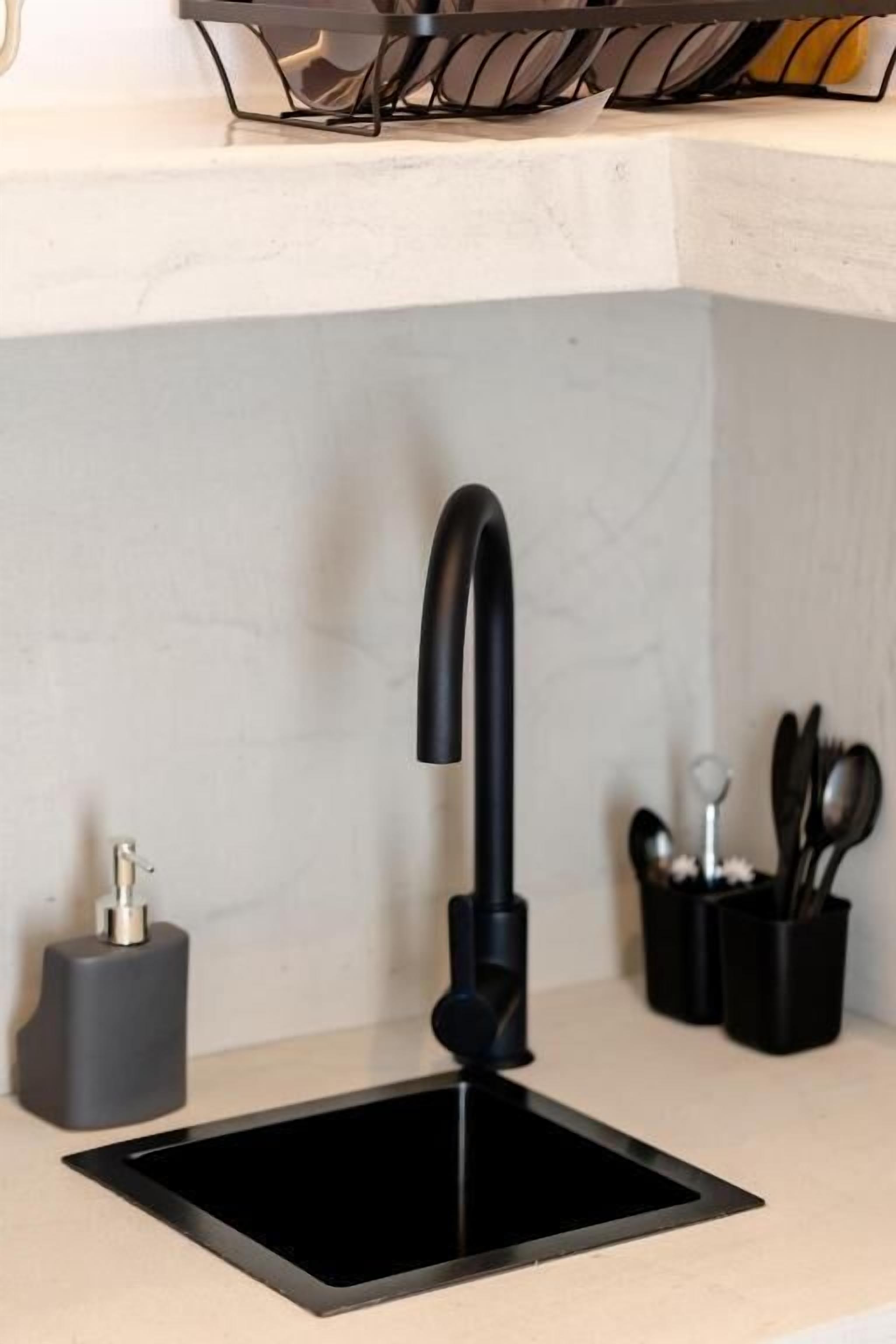 Una cocina moderna con un lavamanos negro, un grifo y un dispensador de jabón.