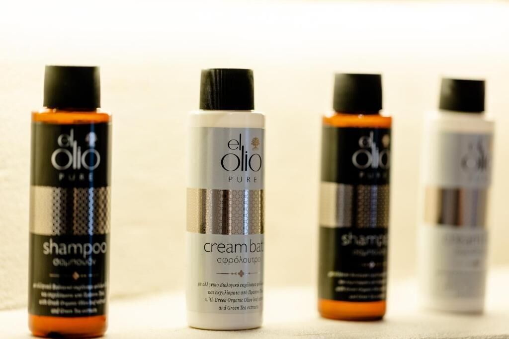 Four bottles of El Olio Pure products, including shampoo and cream balm, arranged in a row.