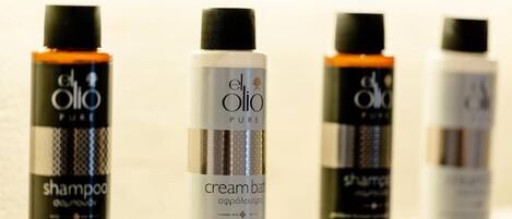 Four bottles of El Olio Pure products, including shampoo and cream balm, arranged in a row.