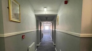 A narrow, carpeted hallway with light gray walls, white trim, and a ceiling light fixture.