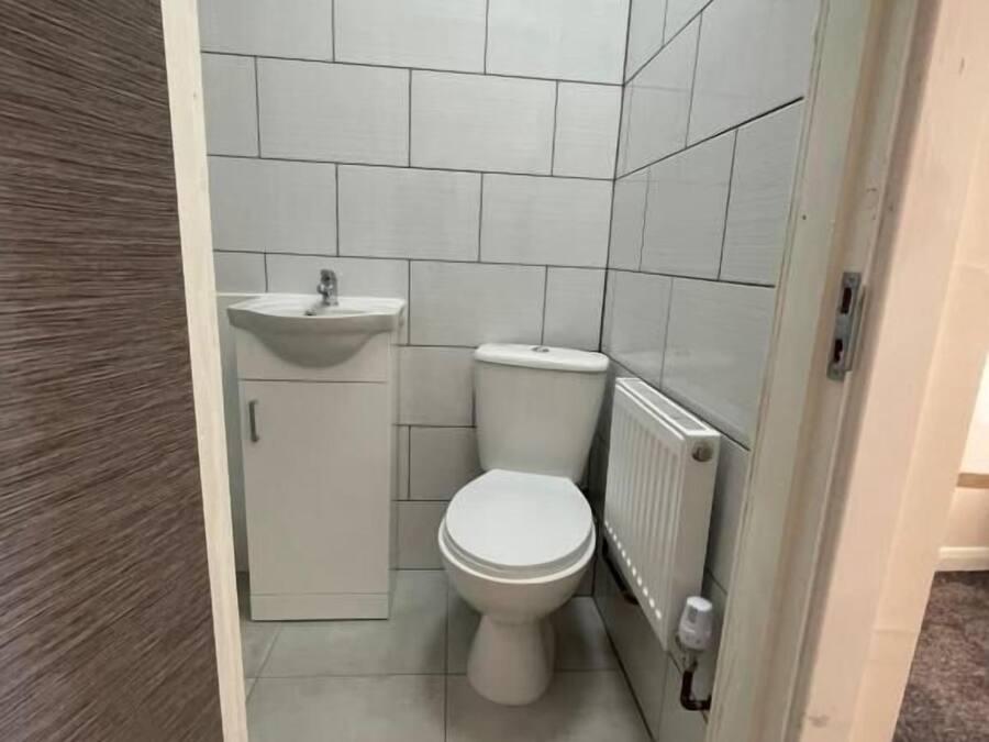 Un baño pequeño y cerrado con inodoro, lavamanos y radiador.
