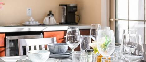 A dining table set with multiple glasses and bowls, a decorative plate, and a vase with flowers.