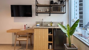 Una cocina moderna con televisor integrado, una mesa de comedor de madera, un lavamanos y una planta en maceta.