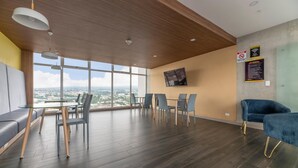 Una sala de conferencias moderna con una mesa de vidrio, sillas y vistas a un paisaje urbano a través de amplias ventanas.